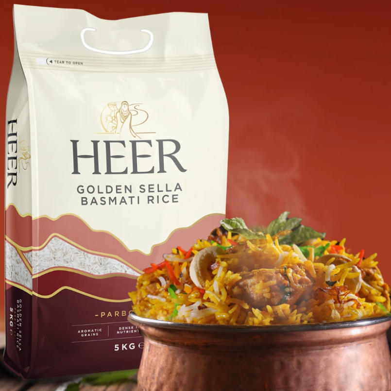 HEER Golden Sella Basmati Rice package with a bowl of rice dish on a wooden surface.