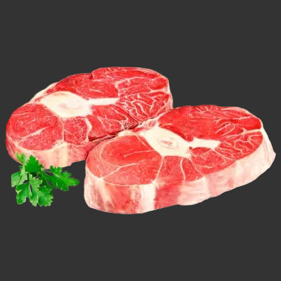 Two pieces of raw red meat with a sprig of parsley on a white background