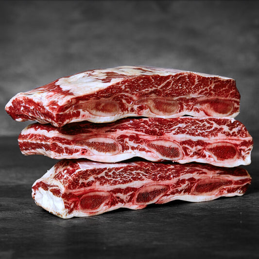 Three stacked pieces of raw beef on a dark background